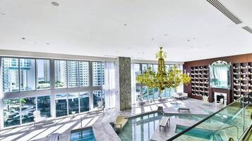 A spacious indoor area with a large pool, seating, and a grand chandelier.