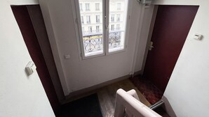 A narrow stairway leading to a balcony with a view of buildings.
