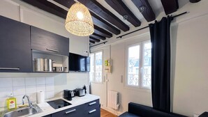 A modern kitchen with dark cabinets, a built-in oven, a sink, and a hanging light fixture.