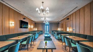 A spacious dining area with multiple tables and chairs, a central chandelier, and a television screen on the wall. - Corner 2BR · 42nd Floor Bay & City Views Sleeps 6 (Miami)