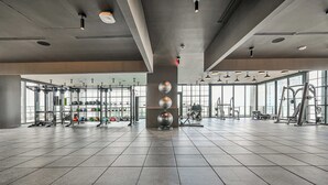 A spacious gym with various exercise equipment, large windows, and a tiled floor. - Corner 2BR · 42nd Floor Bay & City Views Sleeps 6 (Miami)