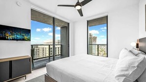 A modern bedroom with a large bed, a ceiling fan, and a city view through floor-to-ceiling windows. - Corner 2BR · 42nd Floor Bay & City Views Sleeps 6 (Miami)