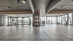 Un gimnasio amplio con diversos equipos de ejercicio, ventanas grandes y un diseño moderno.
