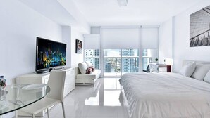 A modern hotel room with a large bed, a TV, a glass dining table, and a city view. - Icon Brickell Studio  City View Pool & Spa (Miami)