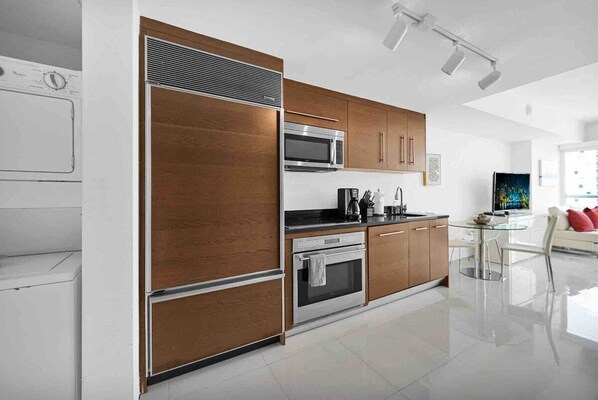 A modern kitchen with stainless steel appliances, wooden cabinets, and a glass dining table.