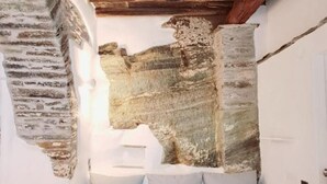Una escalera con un muro de piedra y techo de madera.