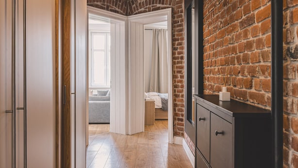 A hallway with a brick wall, a wooden floor, and a bed in the background. - Apartament Terra r Dmie cie nad sam Mot aw (Gdańsk)