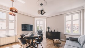 A modern living room with a dining area, large windows, and a flat-screen TV. - Apartament Terra r Dmie cie nad sam Mot aw (Gdańsk)