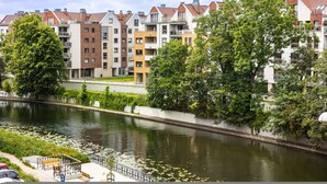 A riverside view with modern apartment buildings, a paved walkway, and a bench. - Apartament Terra r Dmie cie nad sam Mot aw (Gdańsk)