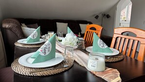 A dining table set with green napkins, white plates, and a candle. - Charming apartment, ideal for longer stays and families (Kiel)