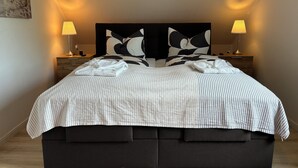 A neatly made bed with a striped bedspread, two black and white pillows, and two bedside lamps. - Charming apartment, ideal for longer stays and families (Kiel)
