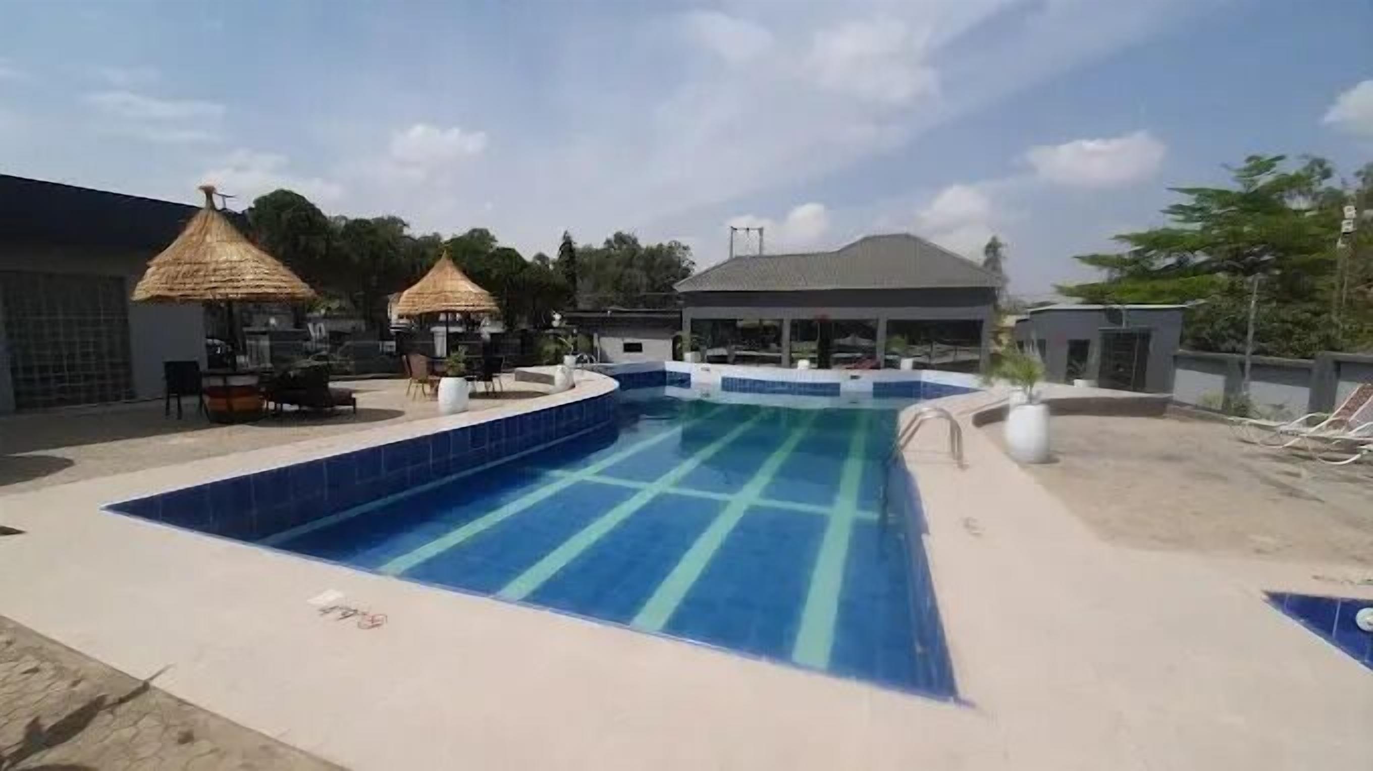 Une piscine dotée d’une terrasse carrelée, entourée de chaises longues et de parasols.