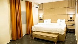 A hotel room with a large bed, a bedside table, an air conditioning unit, and curtains. - Lamonde Hotels by Somewhere (Jos)