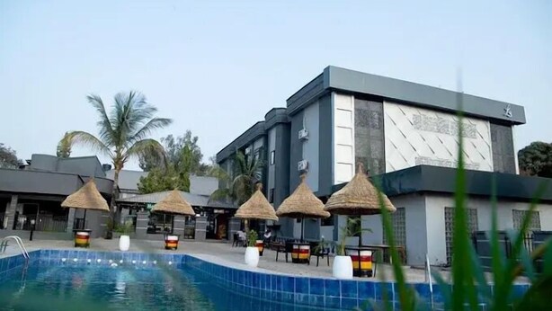 A modern hotel with a swimming pool, thatched umbrellas, and palm trees. - Lamonde Hotels by Somewhere (Jos)