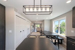 A modern kitchen with a long countertop, built-in cabinets, and a large window providing natural light. - The Birches Condotel Unit 3 (Lake Leelanau)