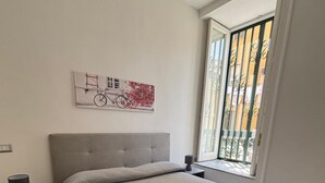 A modern bedroom with a large bed, a nightstand, a window with a view, and a wall art piece.