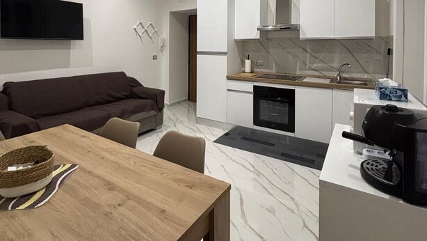 A modern kitchen with white cabinets, a built-in oven, and a coffee maker on the counter.