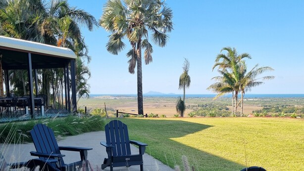 A patio with two Adirondack chairs, a covered seating area, and a view of the landscape. - Doug's Place - Spectacular Views + Tennis Court (Nindaroo)