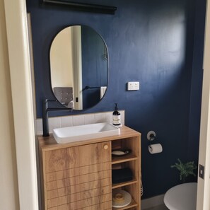 A bathroom with a white sink, a mirror, and a wooden vanity. - Doug's Place - Spectacular Views + Tennis Court (Nindaroo)