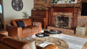 A living room with a leather sofa, a coffee table, and a fireplace. - Doug's Place - Spectacular Views + Tennis Court (Nindaroo)