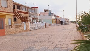 Un sendero pavimentado con edificios a un lado y una palmera al otro.
