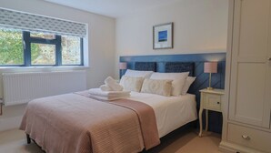 A neatly arranged bedroom with a bed, bedside table, and a wardrobe. - 1 Mill Green Court (Lyme Regis)