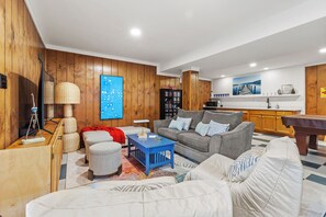 Un salon comprenant un canapé, un pouf, une table basse et un téléviseur.