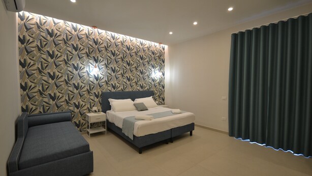 A modern bedroom with a bed, bedside tables, and a sofa.
