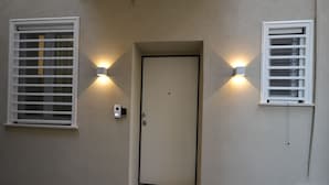 A door with a small window above it, flanked by two wall-mounted lights.