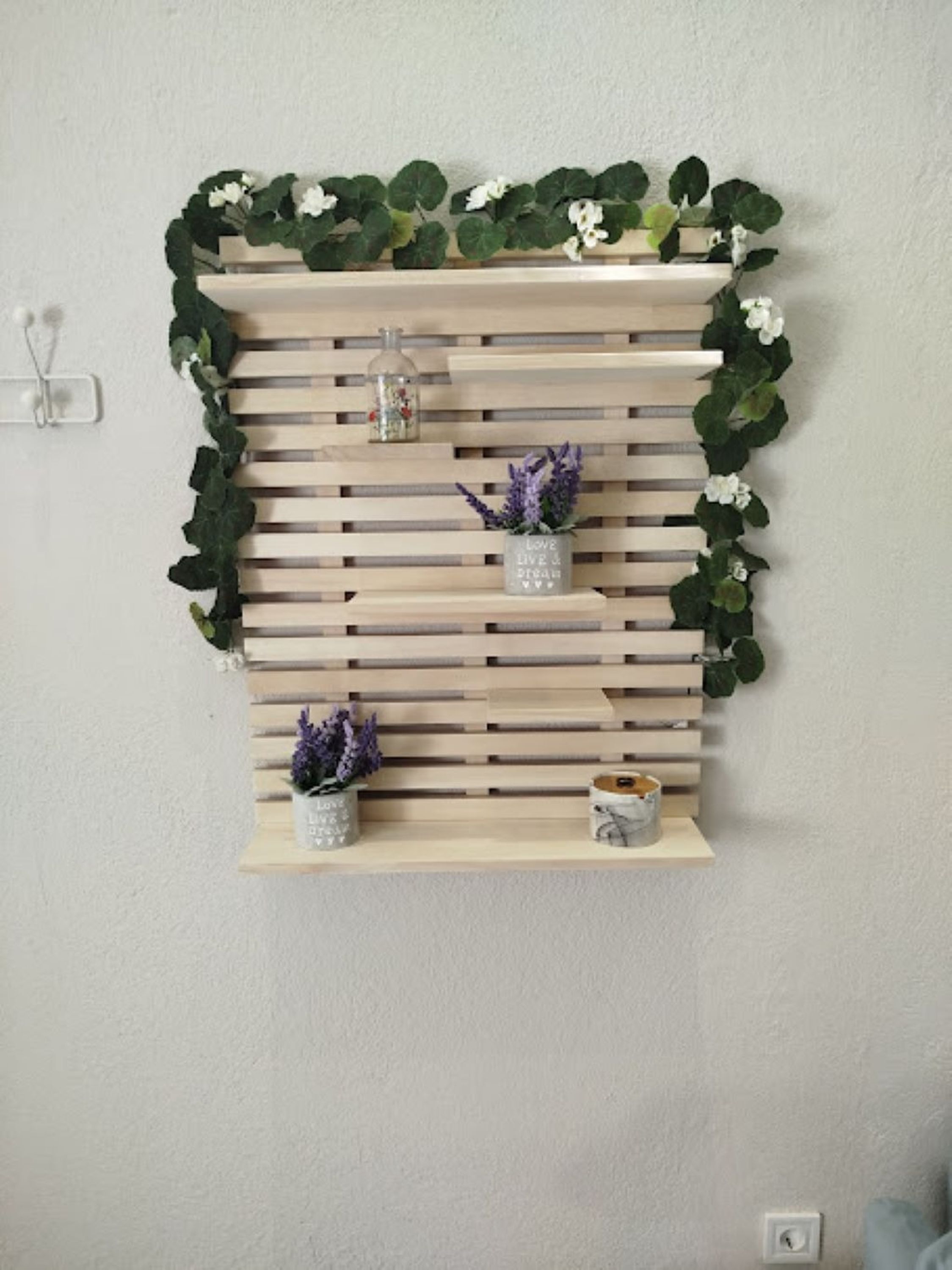 Una estantería de pared con dos macetas y una botella de vidrio.