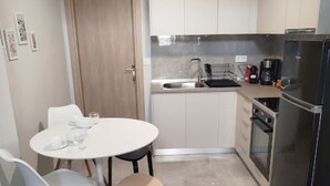A compact kitchen with a dining area, including a table, chairs, and a refrigerator.