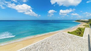 A beach with clear turquoise waters, a sandy shore, and a pebbled area in the foreground.