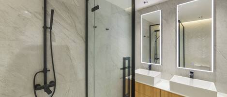 A modern bathroom with a glass-enclosed shower, two sinks with mirrors, and a wooden vanity.