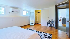 A bedroom with a bed, a chair, a wardrobe, and a door leading to another room. - Willie's Hill Country Hideaway - Family Stay for 8 with Hot Tub & Fire Pit (Wimberley)