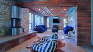 A spacious living area with a stone fireplace, sofas, and a large rug.