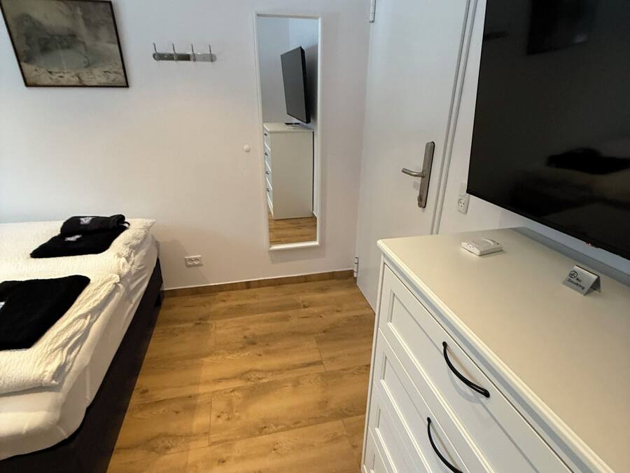 A bedroom with a bed, a dresser, a TV, and a mirror.