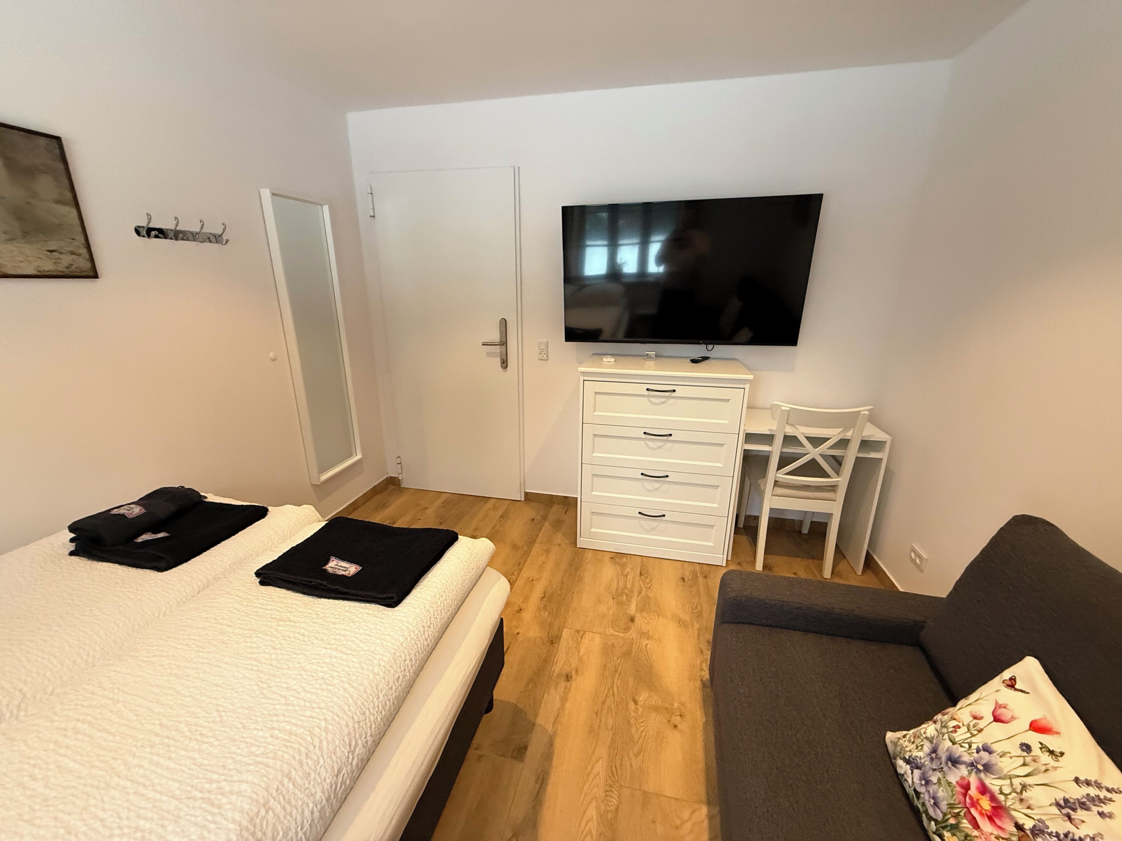 A bedroom with a bed, a desk, a chair, and a TV.