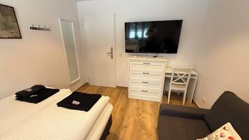 A bedroom with a bed, a desk, a chair, and a TV.