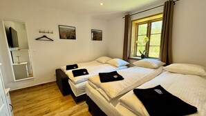 A hotel room with two beds, a wooden floor, a window with curtains, and a mirror. - Casa de Rainer Tommerup (Tommerup)