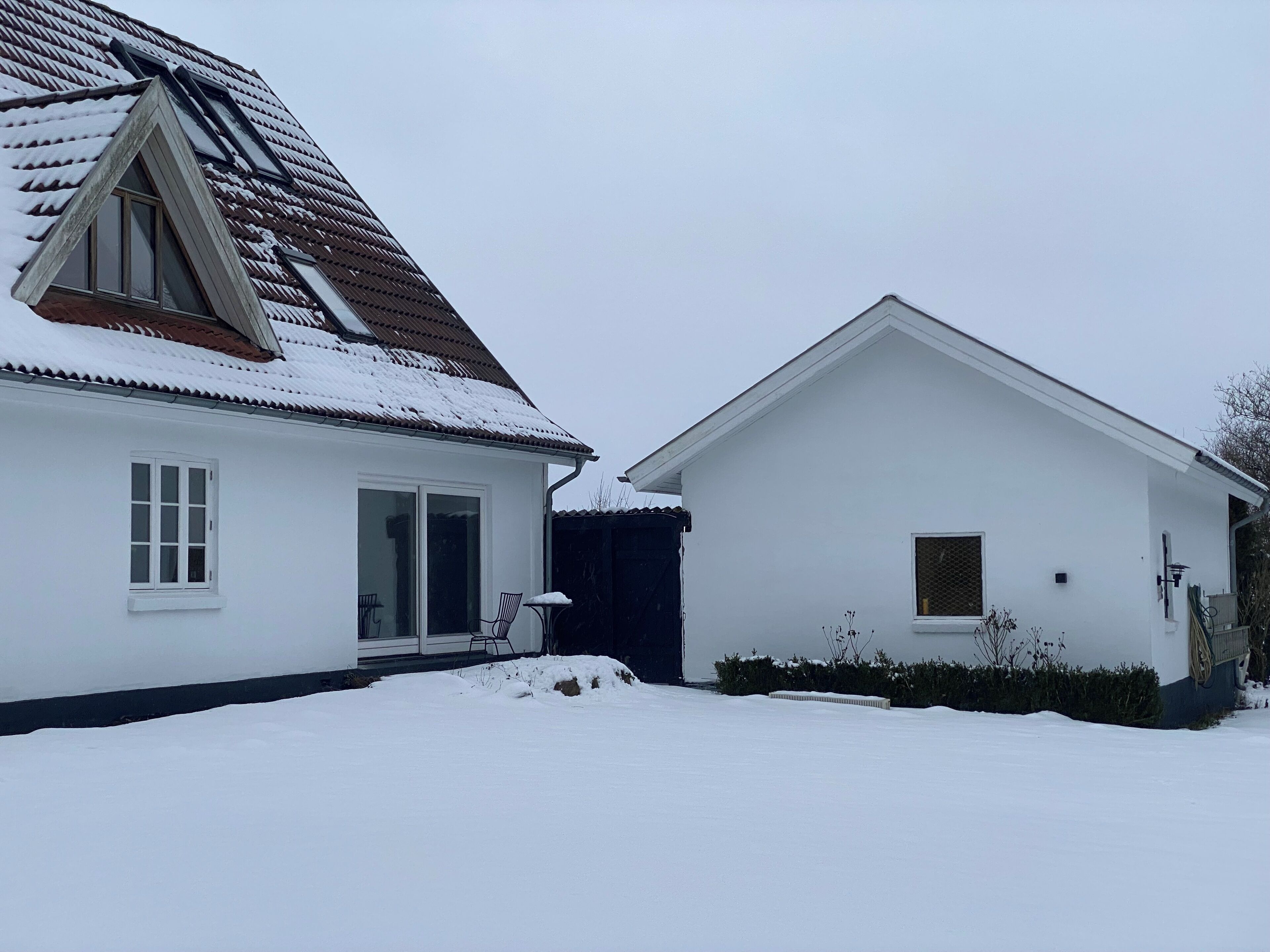 Dos casas blancas con tejados nevados y un cielo despejado.
