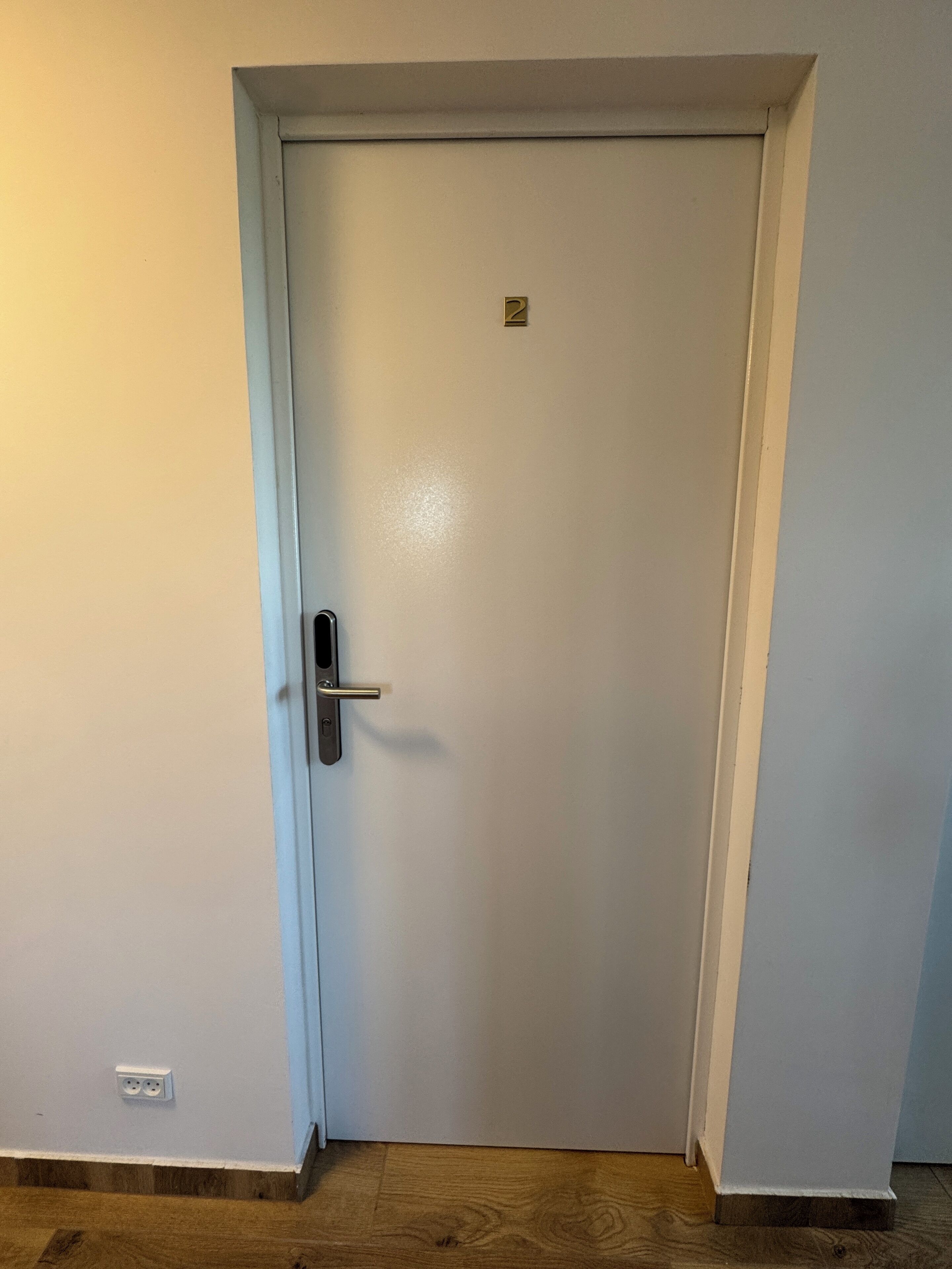 A closed white door with a silver handle and a small square lock plate.