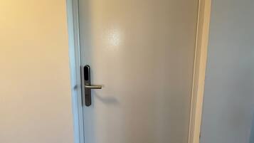 A closed white door with a silver handle and a small square lock plate.