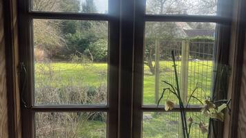 Una habitación con un ventanal grande, una planta en maceta y una mesita.