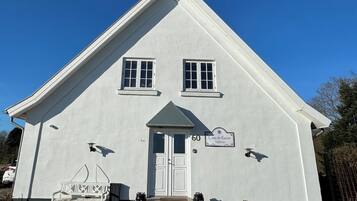 A two-story building with a gabled roof, a front door, and two windows.