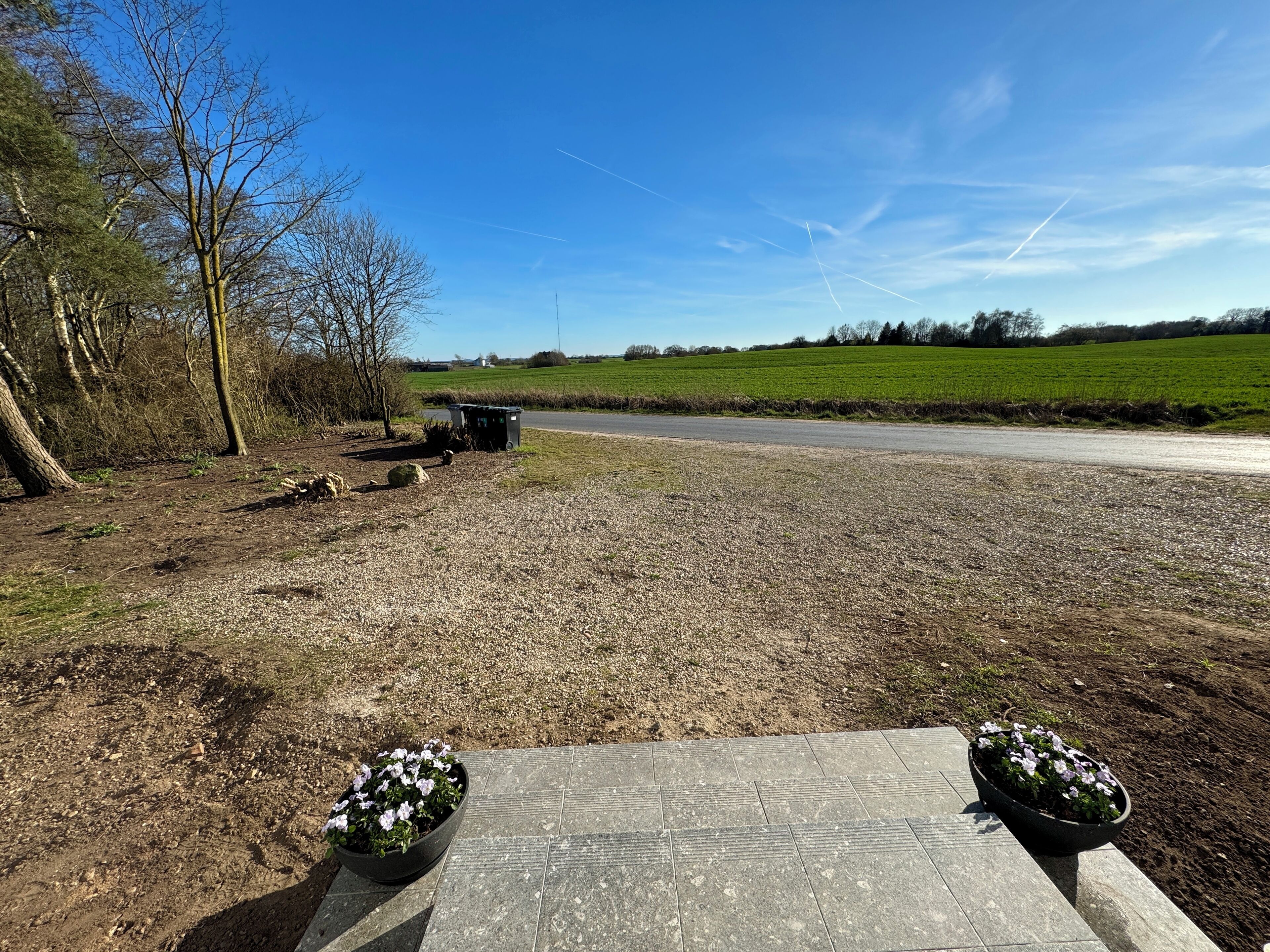 A paved area with two flower pots, a gravel path, and a road in the background.