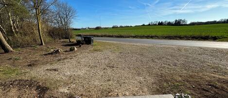 A paved area with two flower pots, a gravel path, and a road in the background.