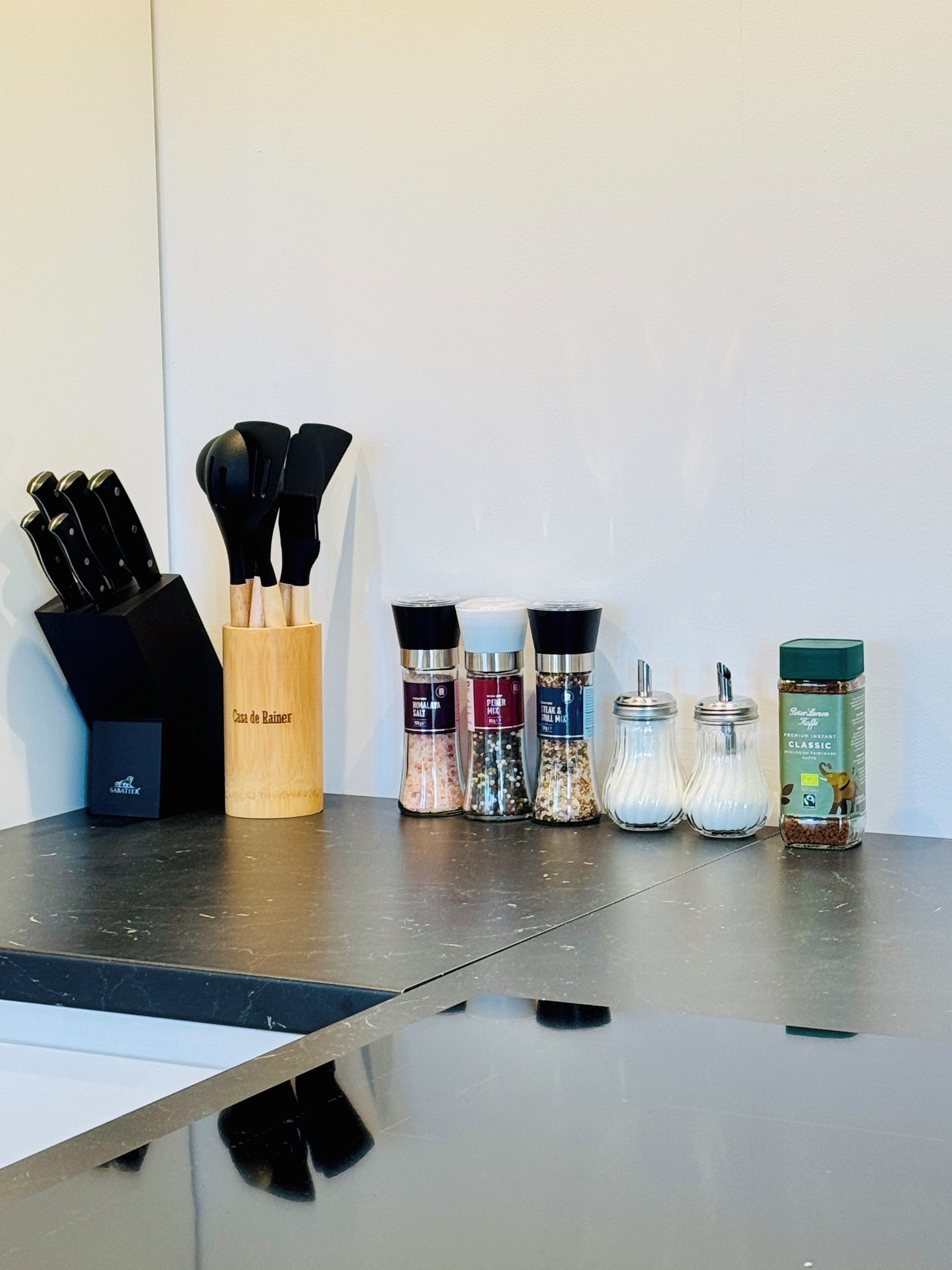 A kitchen counter with various cooking utensils and spice containers.