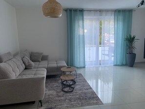 A modern living room with a sectional sofa, a small round table, and a potted plant. - Stylish apartment (Paderborn)