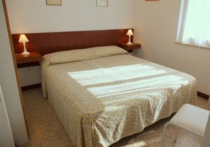 Una cama individual con una colcha estampada, dos lámparas de noche y una mesita de noche.