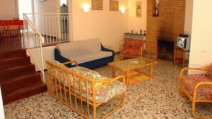 A living room with a sofa, armchairs, a coffee table, a fireplace, and a TV. - Nice an welcoming villa with patio and garden (Lignano Sabbiadoro)